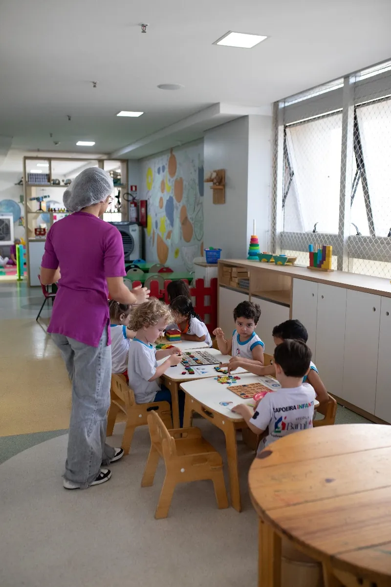 Crianças manipulando materiais concretos com apoio da educadora
