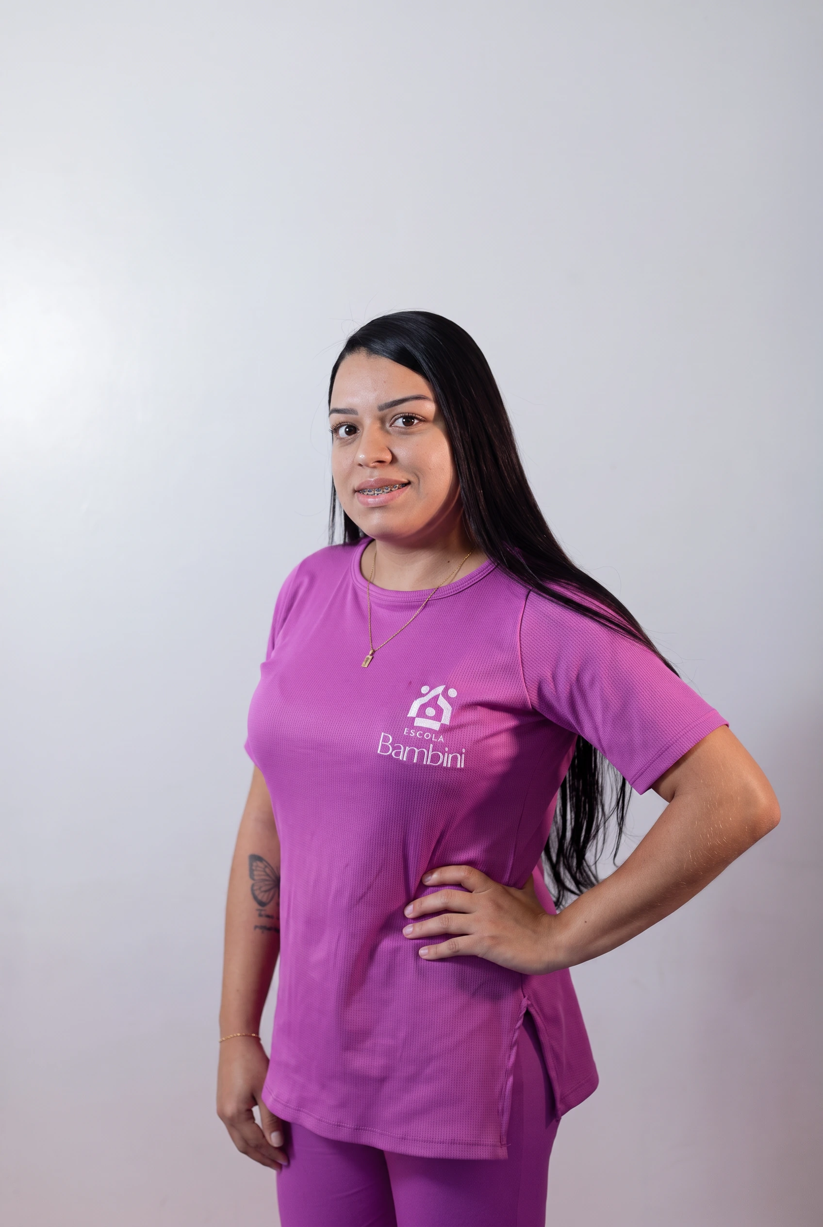Bianca Guimarães, auxiliar de coordenação, vestindo uma camiseta roxa com o logo da escola Bambini